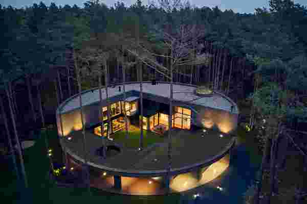 This circular house is inspired by a cut tree trunk & was made to blend into the surrounding pine forest!
